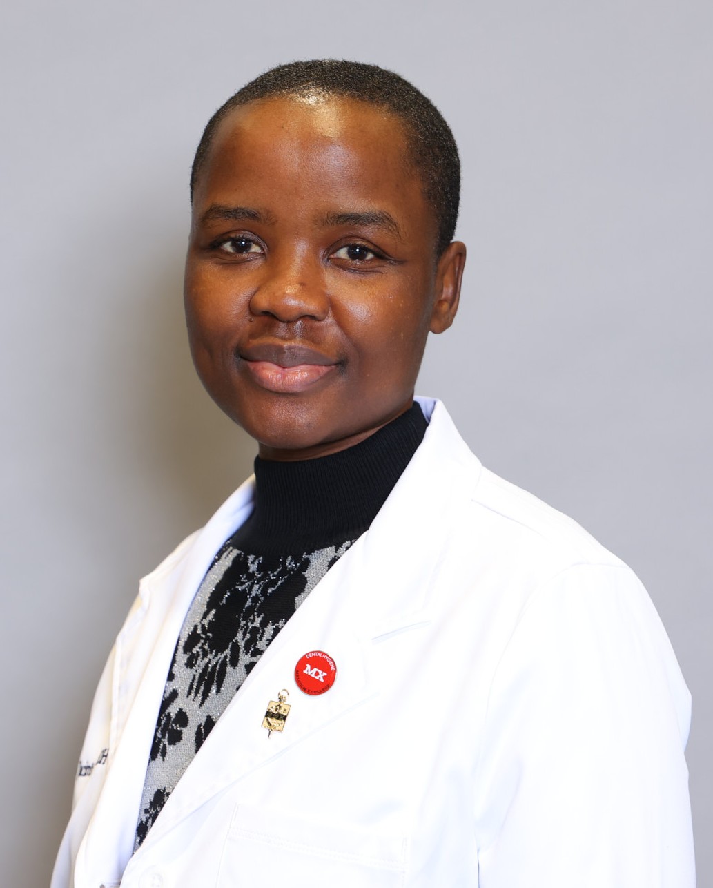 Jacinter Lumumba, RDH, wearing a white clinical coat